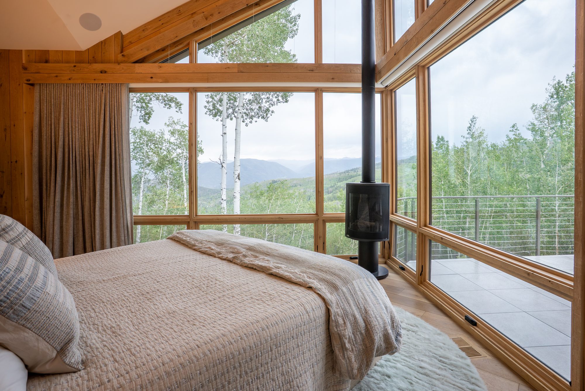A bedroom under glass, looking out to aspens and the valley beyond