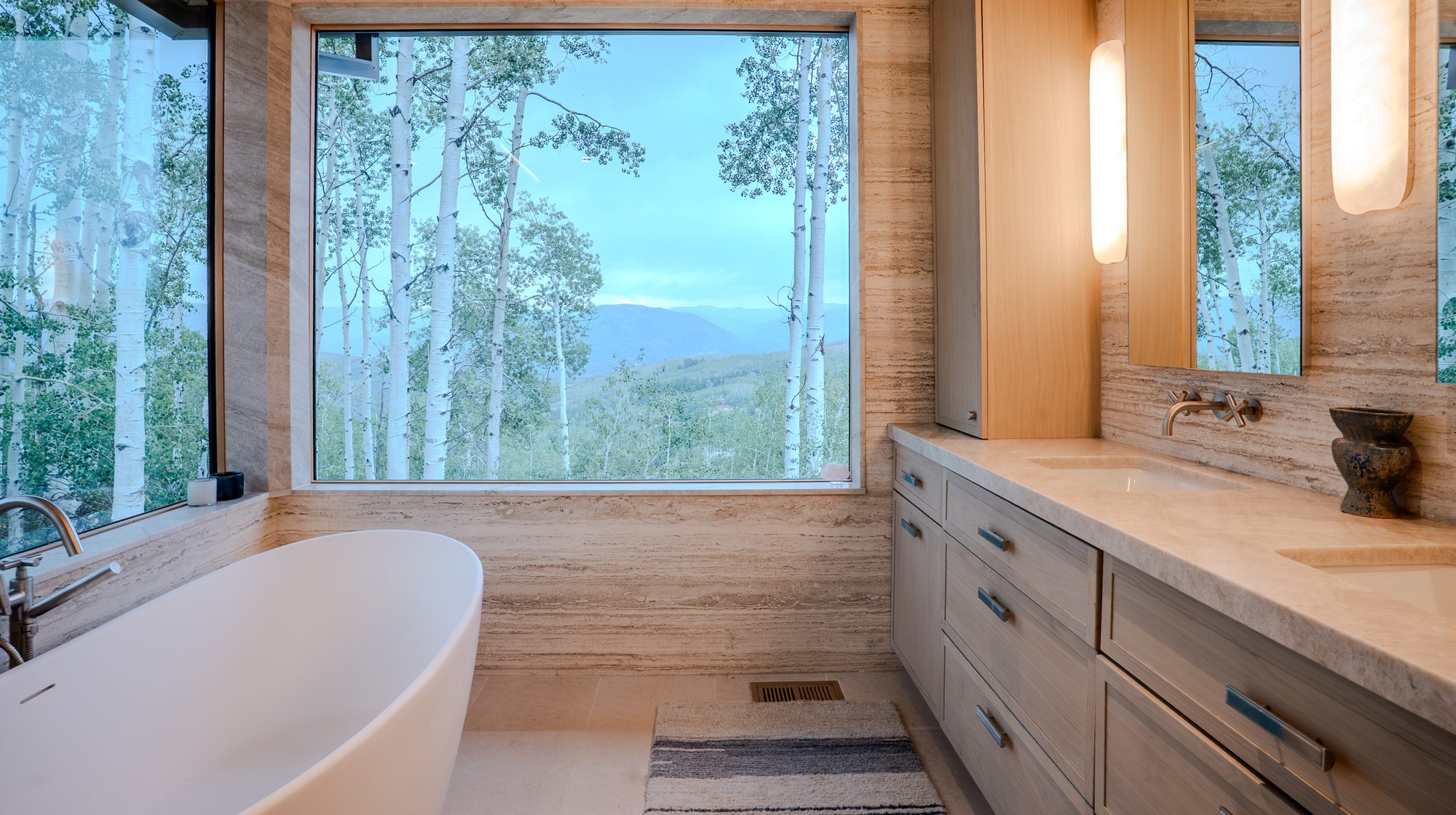 A freestanding bath before a window of aspens and mountains