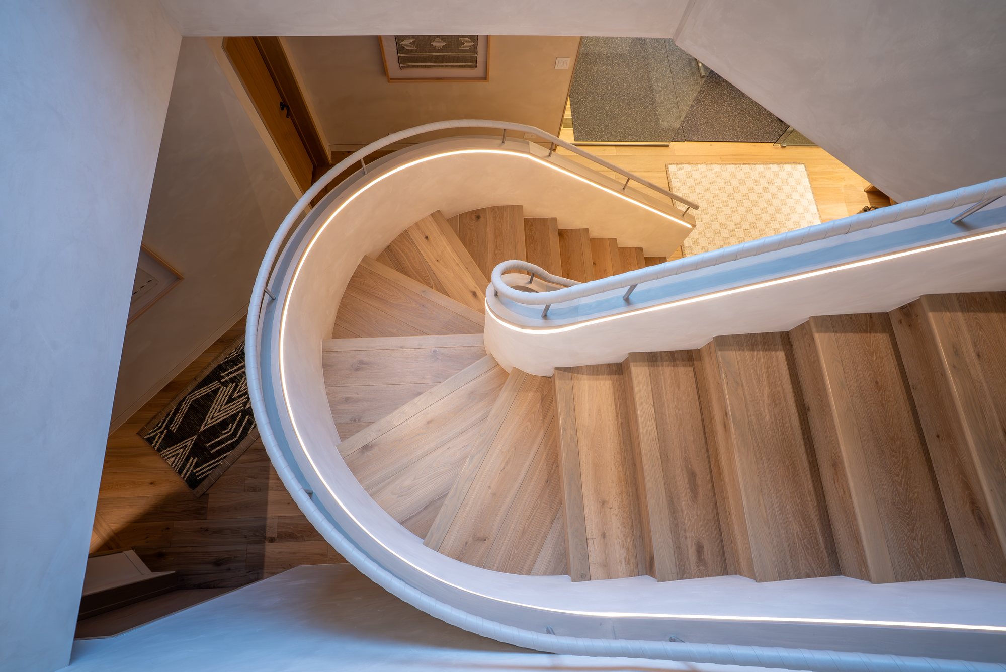 The spiral stair seen from above, lit by a continuous rail of light