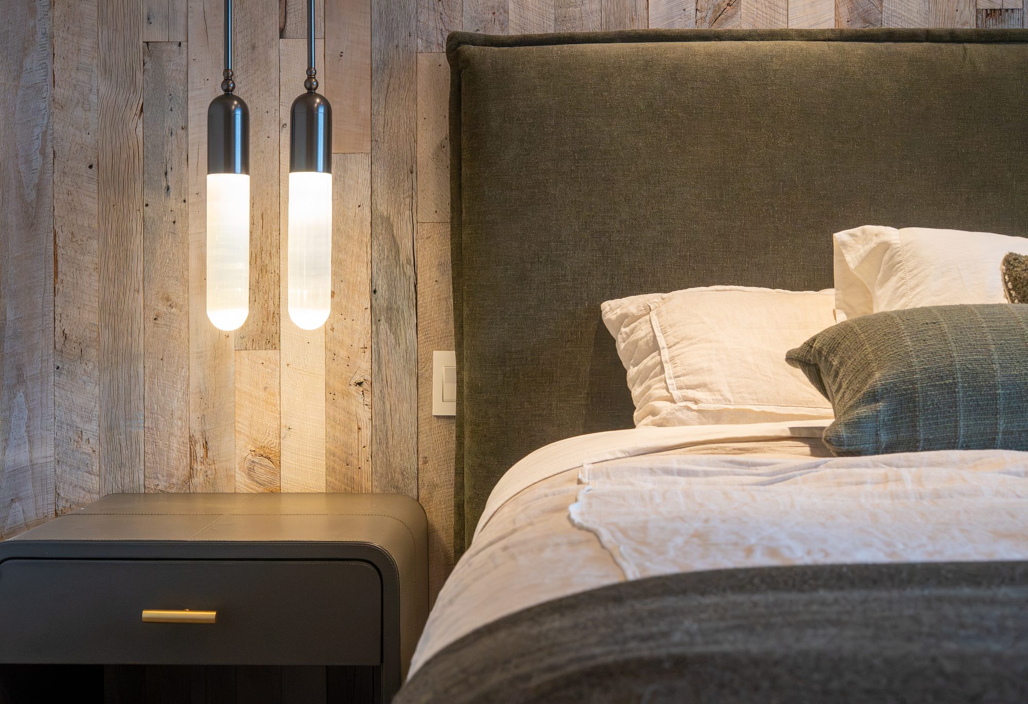 Pendant light falling across reclaimed timber and linen